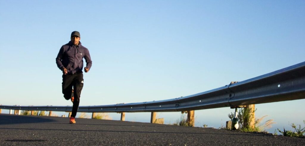 Mies juoksemassa tien reunassa.